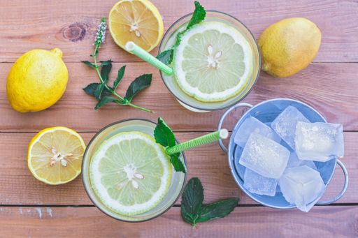 A top view of a messy table with ingredients and glasses of fresh lemonade