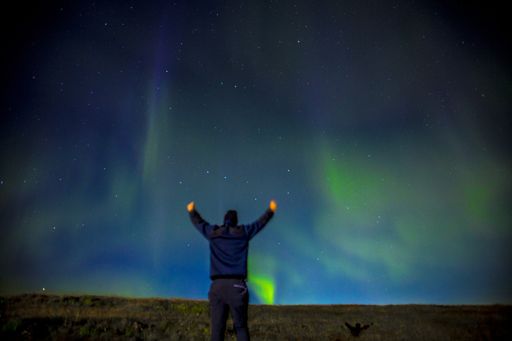 A closeup shot of a male enjoying Northern lights on the Reykjanes Skaginn Peninsula in Iceland