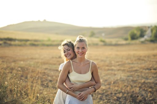 Two young women smiling and hugging each other in the field