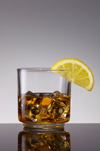 A closeup of a drink with ice and lemon slice