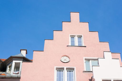 A low angle shot of the top of a pink building against the blue sky
