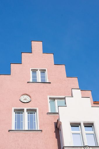A vertical low angle shot of the top of a pink building against the blue sky