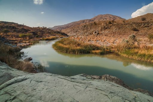 A landscae view of a river surrounded by grass and cliffs