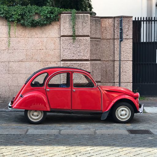 A parked classic French red Citroen 2CV
