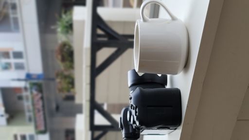 A vertical shot of a cup of coffee and a camera on the balcony