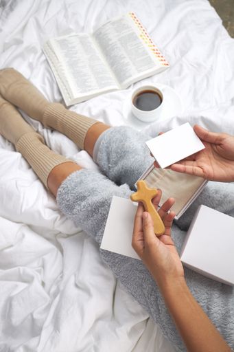 A vertical shot of a female holding a wooden cross, gift box and card with space for text