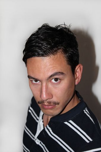 A closeup of a Young hipster with mustache looking at camera with raised eyebrows
