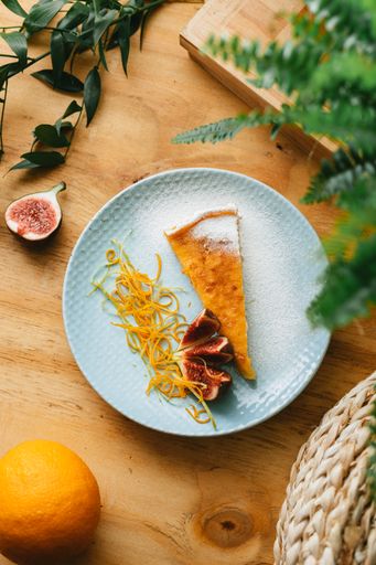 A vertical closeup of the piece of orange cheesecake tart with fig.