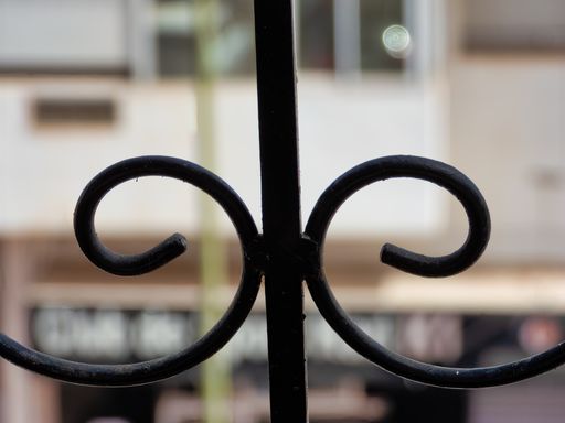 A closeup of a metal fence in the daylight with a blurry background