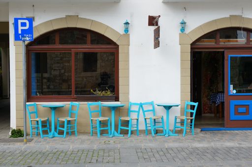Blue chairs and tables in front of a restaurant in the city