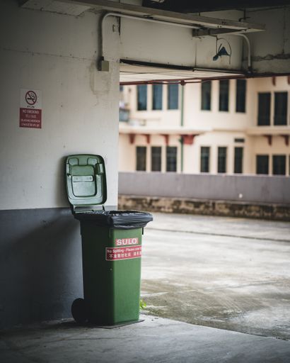 A rubbish bin at the corner of a building
