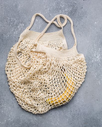 A vertical closeup shot of banana in a beige knitted bag