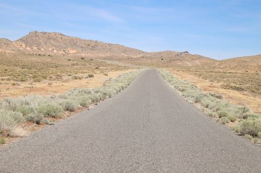 A desolate band of asphalt road continues toward the mountains in the distance.