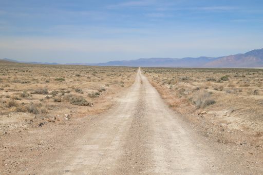 A dirt double track road runs through the barren Nevada desert.