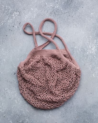 A vertical closeup shot of a dark dusty pink knitted bag