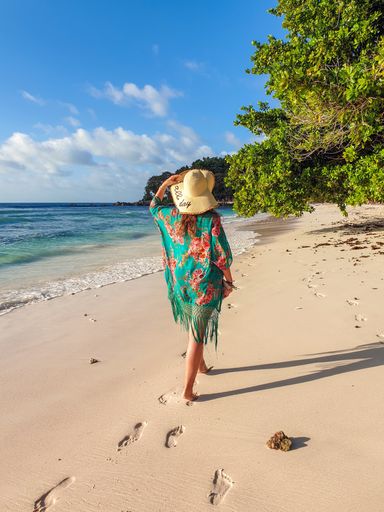A young female walking on an idyllic tropical sandy beach on La Digue island in Seychelles