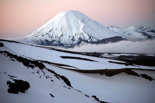 A scenic view of a mountain peak covered with snow, above the clouds