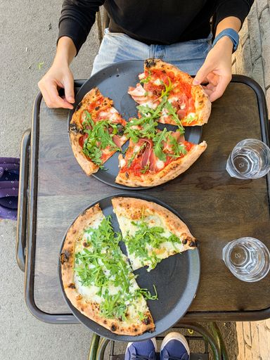A vertical overhead shot of pizza slices on black plates on a wooden table