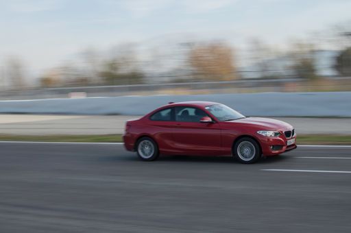 A Red BMW 2 Series driving on a racing circuit in Barcelona, Spain