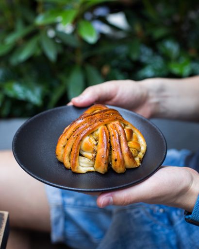 A vertical selective closeup shot of a person holding a plate with a pastry