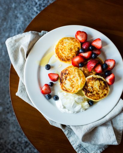 A vertical selective closeup shot of oladyis,strawberries and blueberries on a white plate