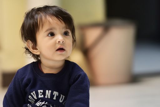 A close-up shot of a cute South Asian baby boy sitting and looking with a curious face