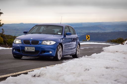 BMW E87 1-Series 130i, blue german hatchback car, on a snowy road in New Zealand.