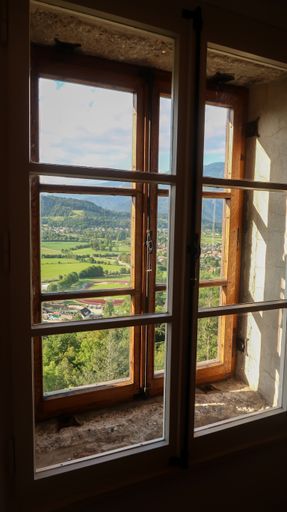 A vertical shot of the Bled town and surrounding mountains through a window