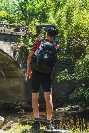 A vertical closeup of the mountaineer taking pictures of a river in Pyrenees.