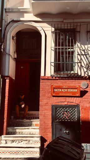 A vertical shot of a person sitting on the stairs in front of the entrance of a house
