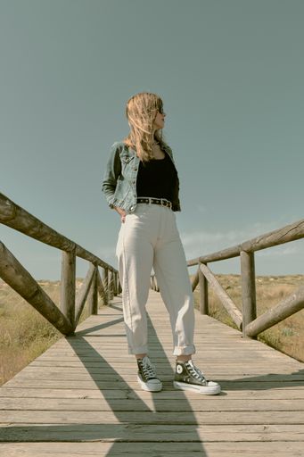 a vertical shot of the Caucasian white model Angela Molina on a wooden bridge on the field