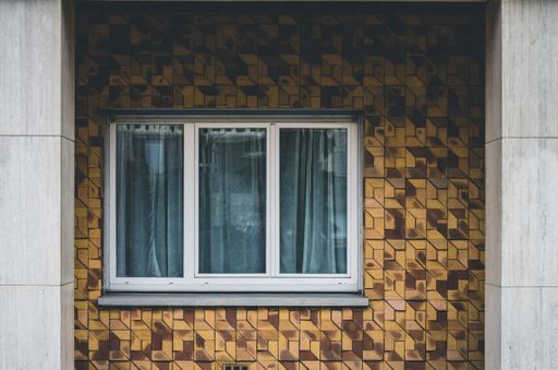 A white window on a brown wall with patterns