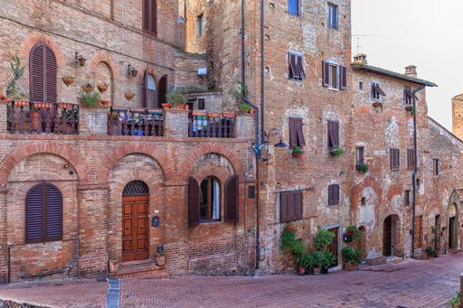 A narrow walkway of old residential buildings with wooden windows in Italy
