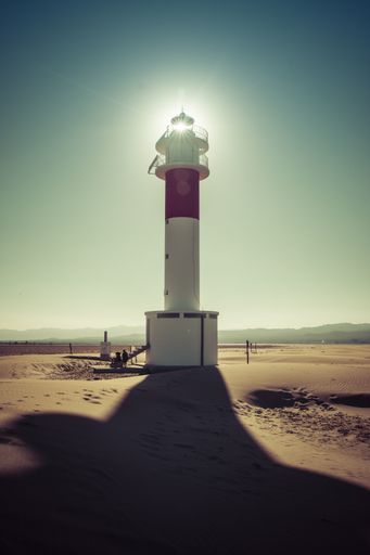A vertical shot of a lighthouse with the sun shining from the back