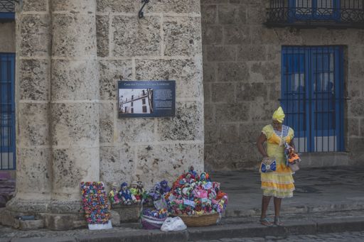 Cuban woman dressed in yellow selling colorful things on the street