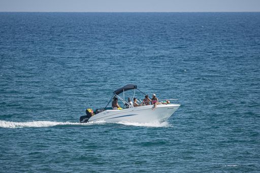 Small white boat, motorboat with a canvas roof by the sea