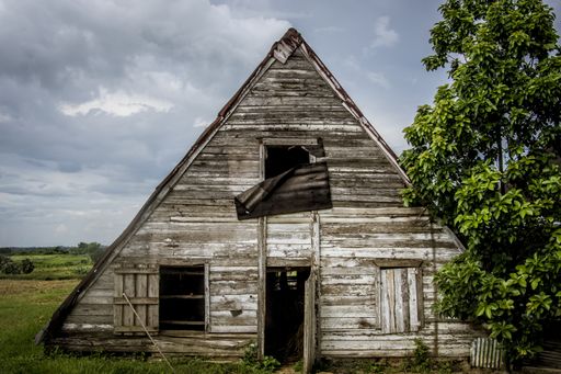 A closeup shot of a triangle-shaped old and weathered creepy abandoned wooden house in a field