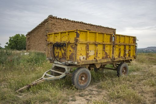 An old rusty tractor-trailer standing on a rural area field