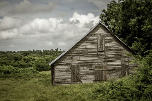 A creepy old wooden abandoned house on a field under the cloudy sky