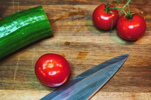 A high angle shot of cherry tomatoes and a cucumber on a cutting board