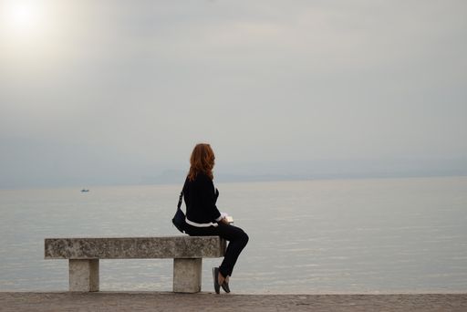 A female enjoying a beautiful view of an ocean while sitting on bench