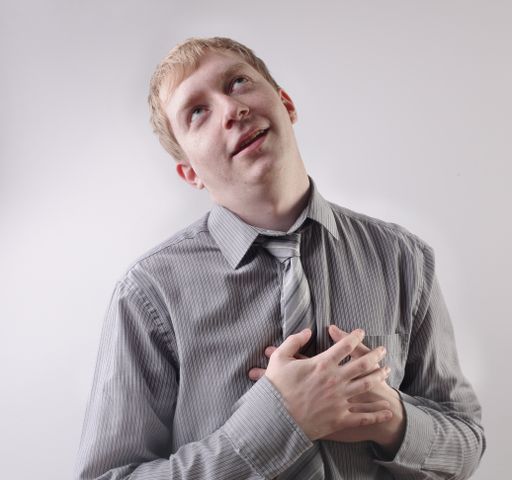 A view of a caucasian male wearing a grey shirt with his hands on his chest - concept: thankful