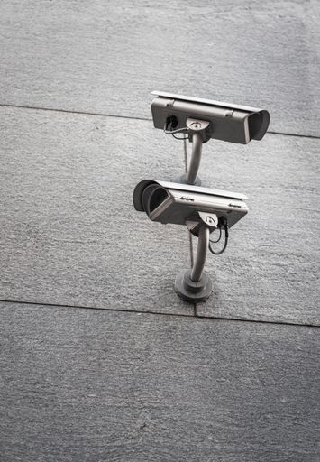 A vertical shot of two street cameras facing opposite directions on a wall
