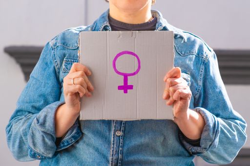 A woman holding a cardboard sign with the female symbol in front of her