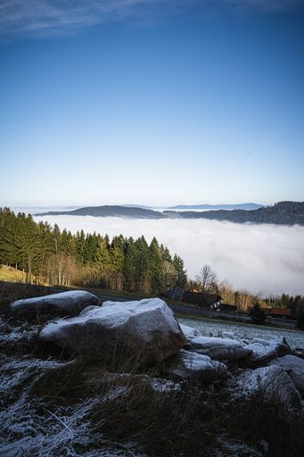 A mesmerizing view of the blue sky over the green hills and the village covered with fog in autumn