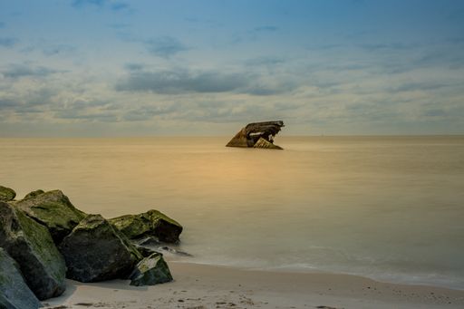 An old abandoned ship on the sea with rocky stones.