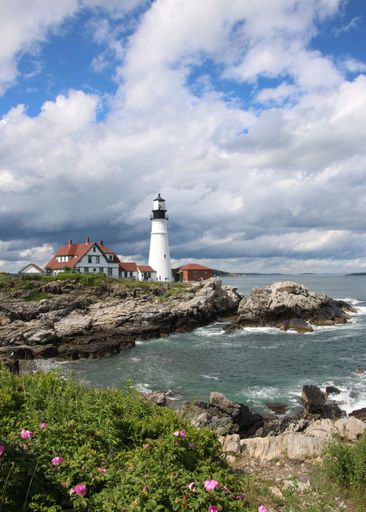 A serene view of a lighthouse on the shore of the ocean in Portland