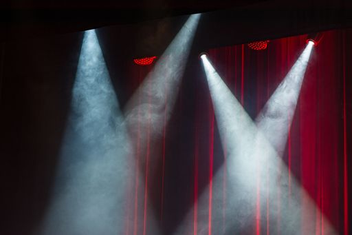A stage with four projects illuminating it