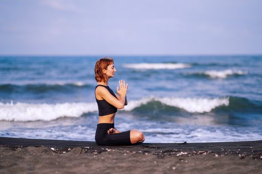 A young Caucasian woman practicing yoga on Zanzibar beach