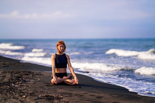 A young Caucasian woman practicing yoga on Zanzibar beach